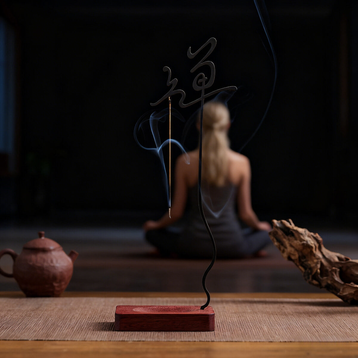 Creating a mindful space: A woman meditates peacefully in a quiet room with the Inverted Zen Incense Holder on her table, a thin line of incense smoke enhancing the tranquil atmosphere.